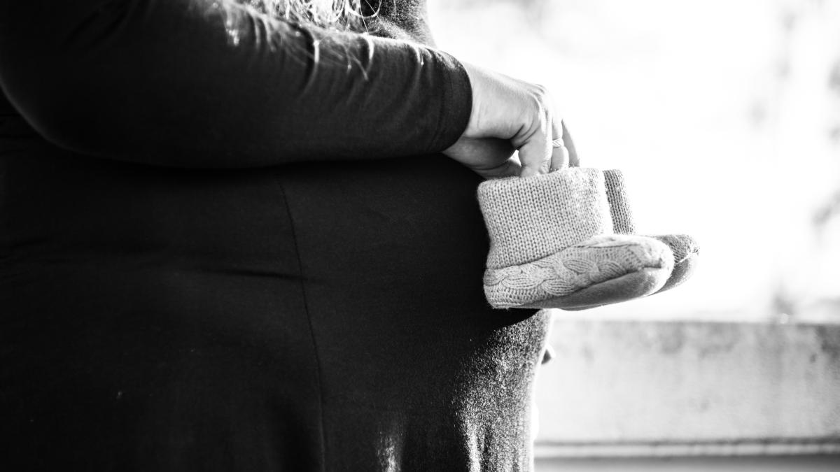 Pregnant woman with baby shoes imagery