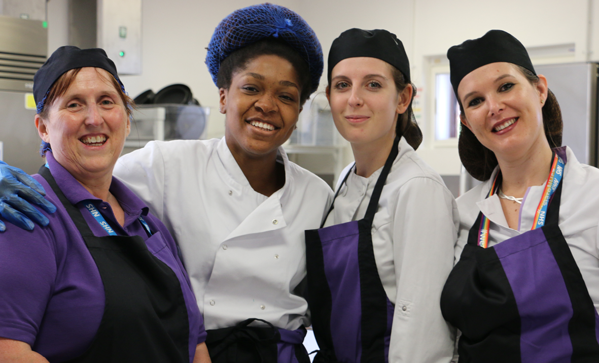 Four colleagues in uniform and aprons smiling