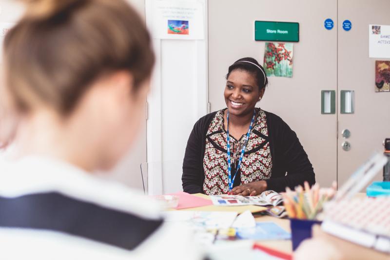 A healthcare worker sits across the table from a woman smiling