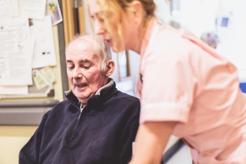 Nurse standing next to a patient in a wheelchair.