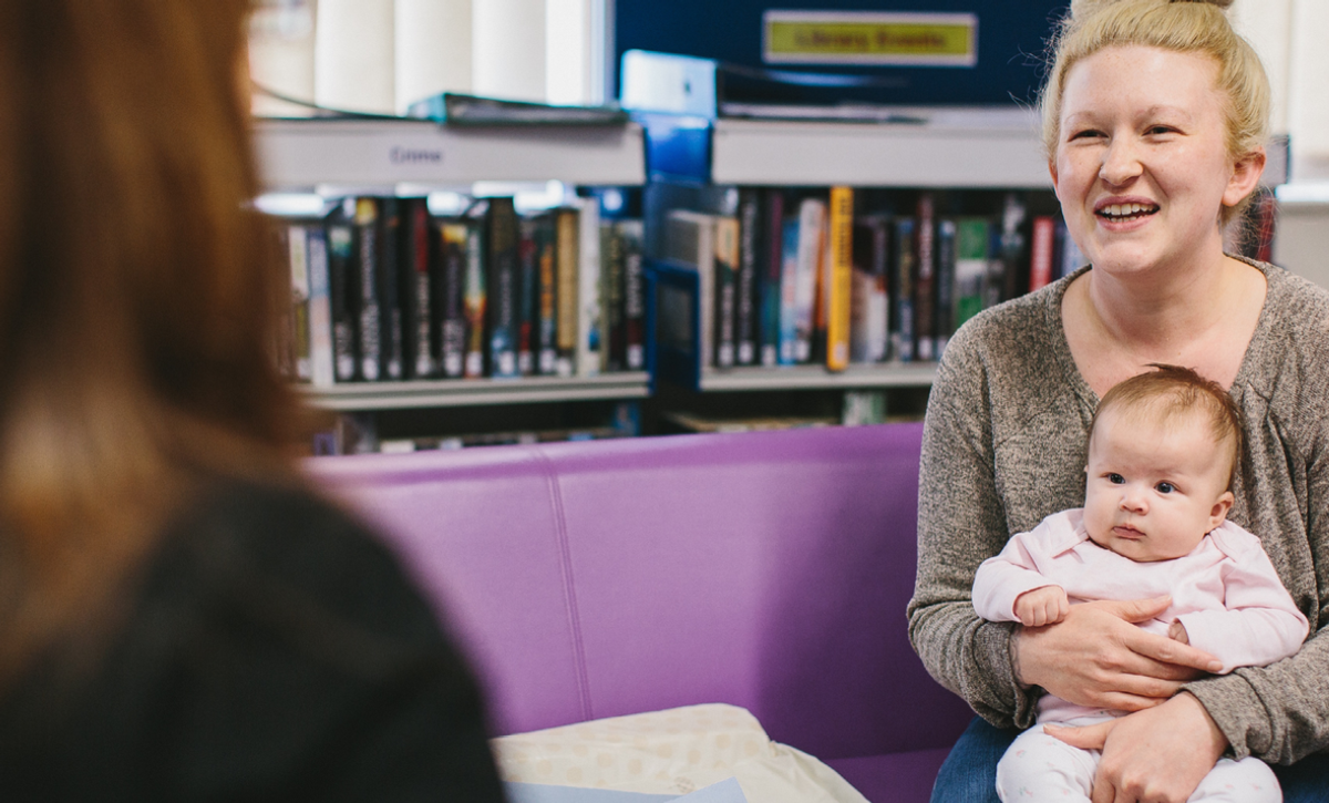 Women smiling holding baby talking to female