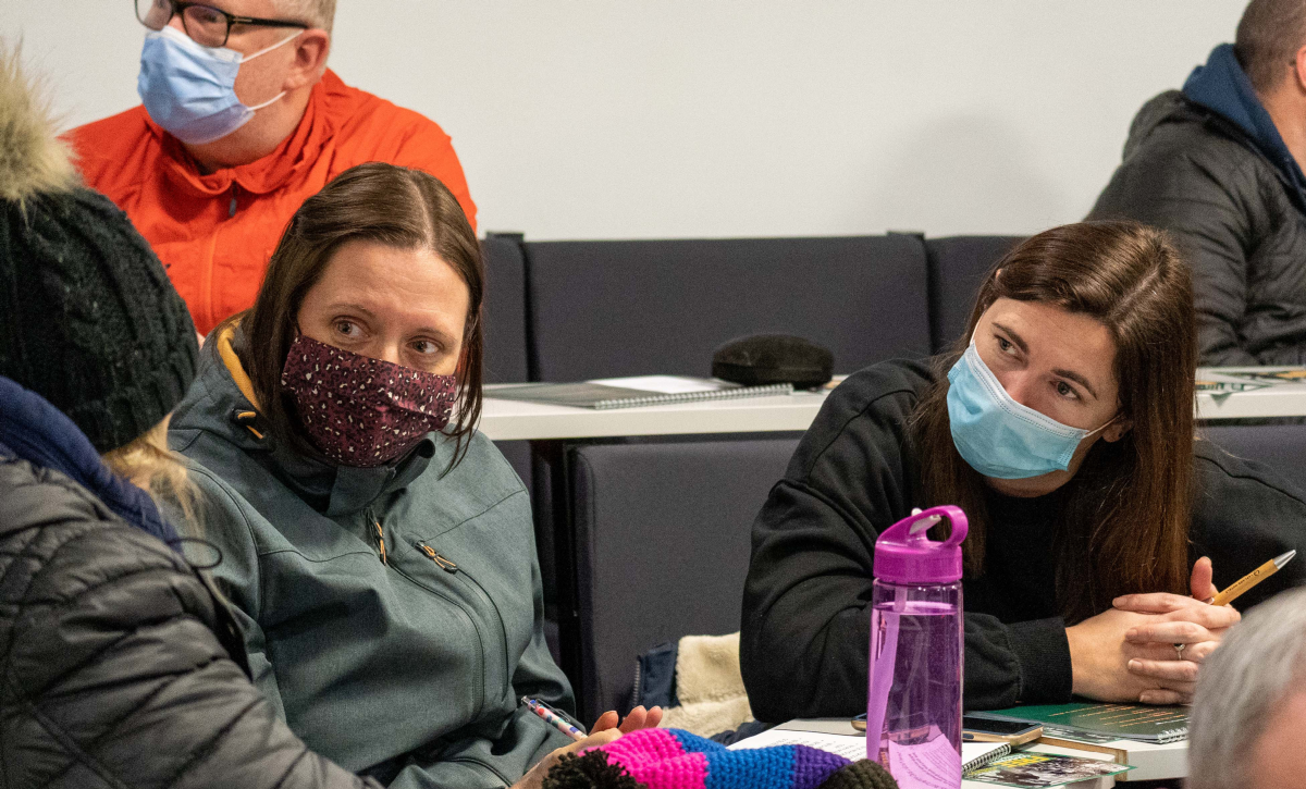 Female participants wearing masks in discussion sat down