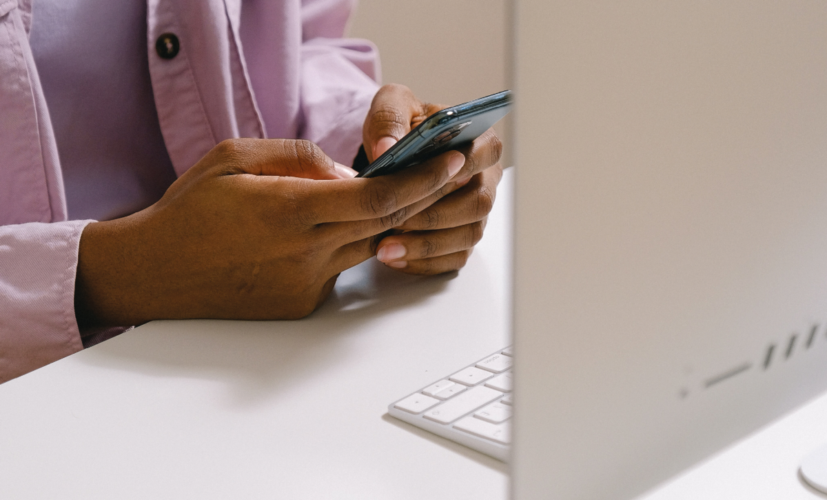 Young person texting on phone sat at desk