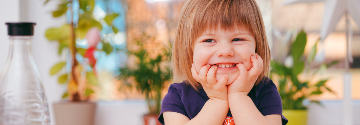 A young child sits smiling facing forward