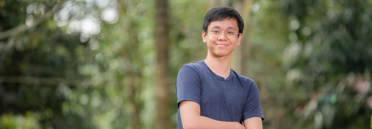 A man stands in a green area smiling to the camera