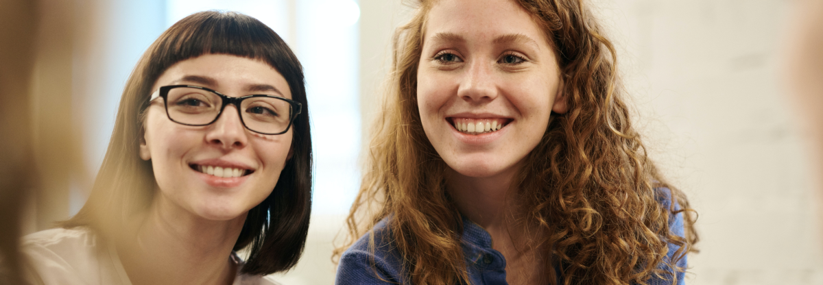 Two teenage girls smile at their friend.