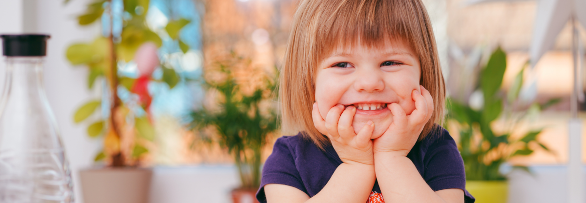 Toddler sits at a table laughing