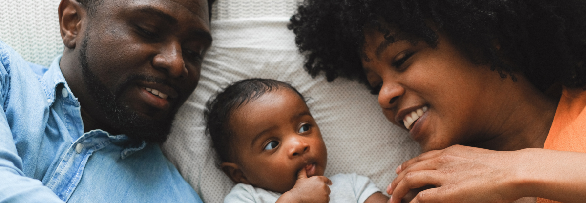 Dad and mum lie with their newborn baby between them