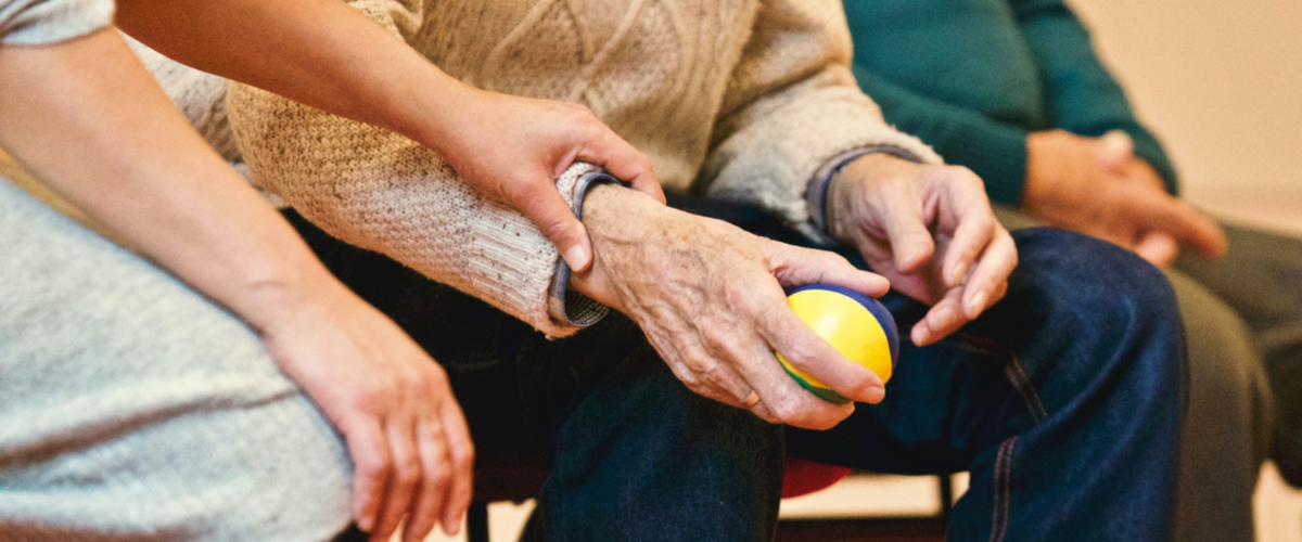 Man holding a ball with a nurse helping him