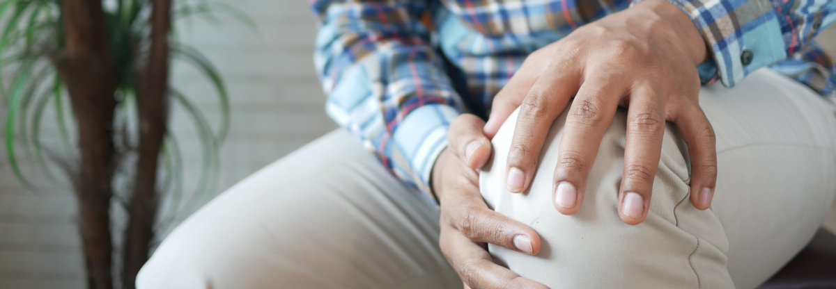Man holds his knee in discomfort