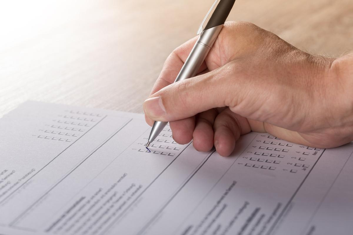 Man's hand writing on a clipboard