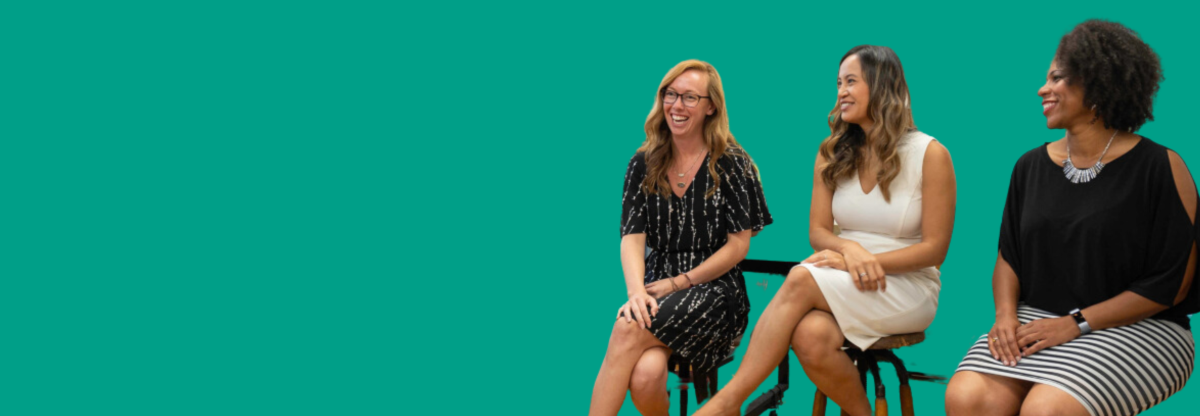 Three women smiling and having a conversation against a green background