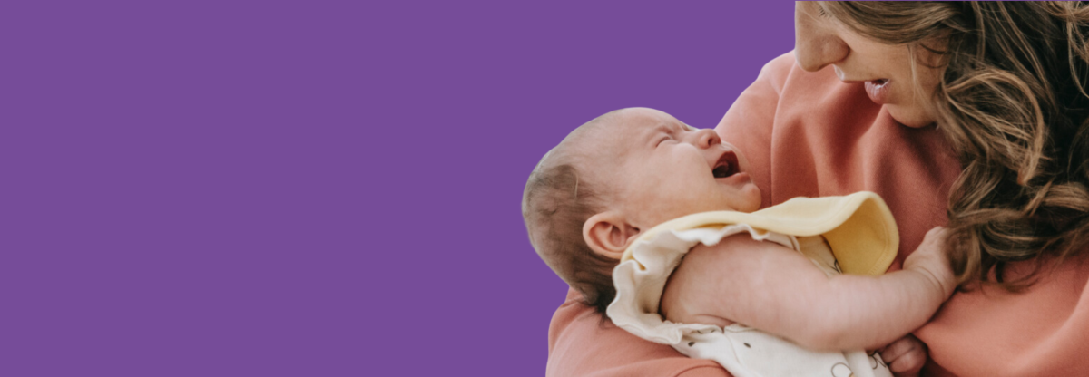 A close-up photograph of a mother cradling a crying baby against a purple background