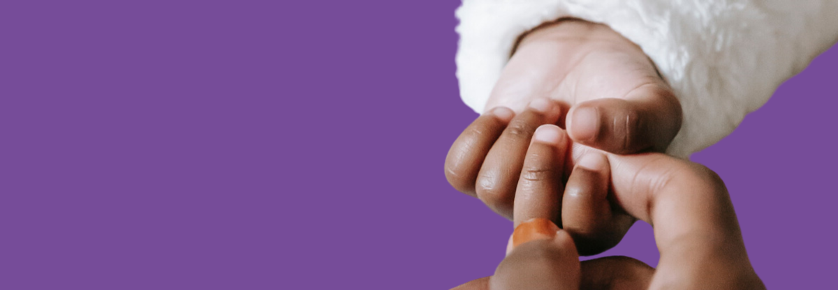 Baby holding mums hand against a purple background