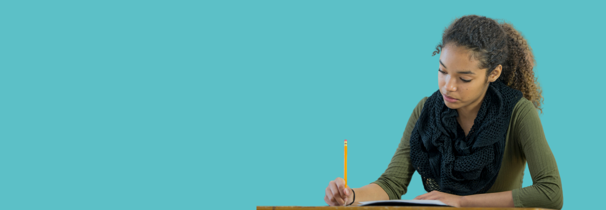 A teenager concentrates while taking an examination against a teal background