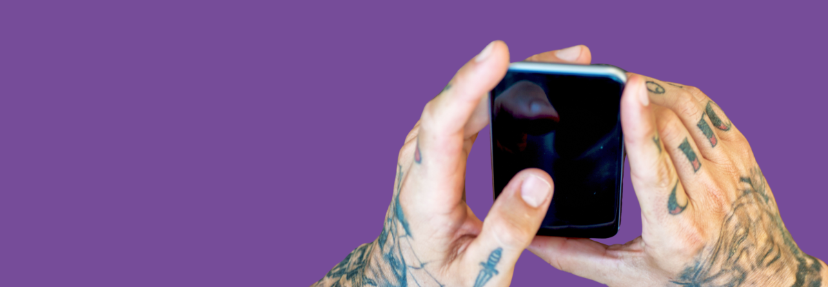 Hands holding a mobile phone against a purple background