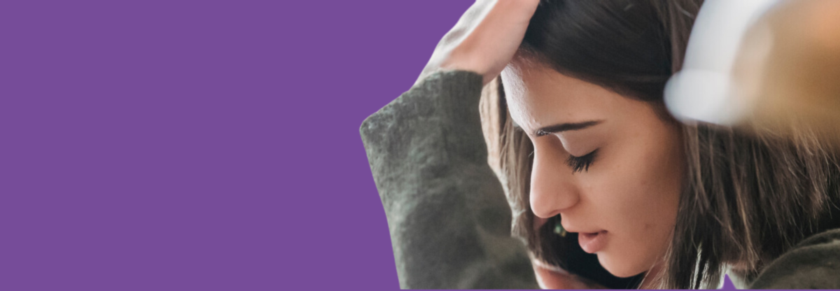 A woman is on the phone and she looks sad against a purple backgorund