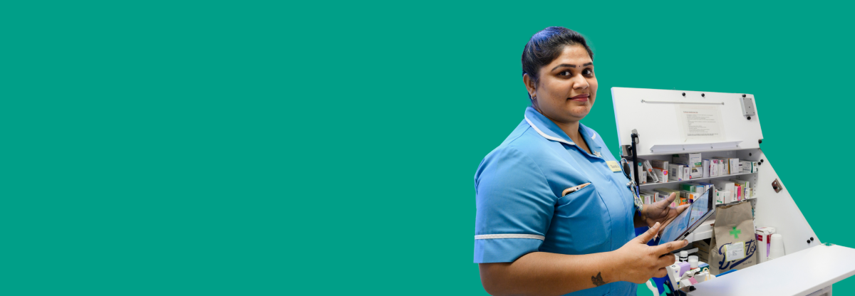 A photograph of an NHFT staff nurse with a handheld tablet device next to a medicine trolley against a green background