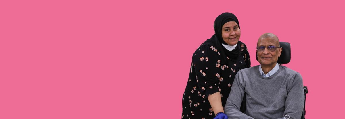 A cutout image of an older man seated in a motorised wheelchair with a younger female carer against a pink background