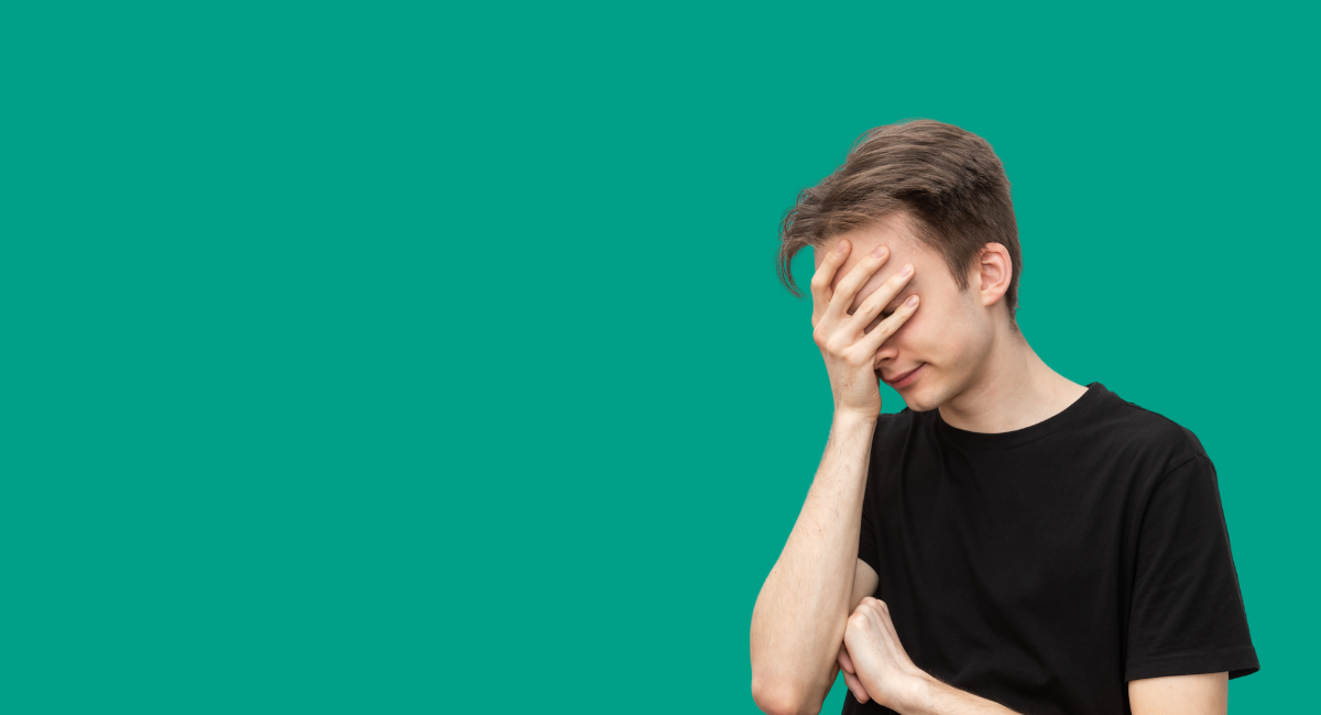 A young man with his head in his hands, looking stressed out